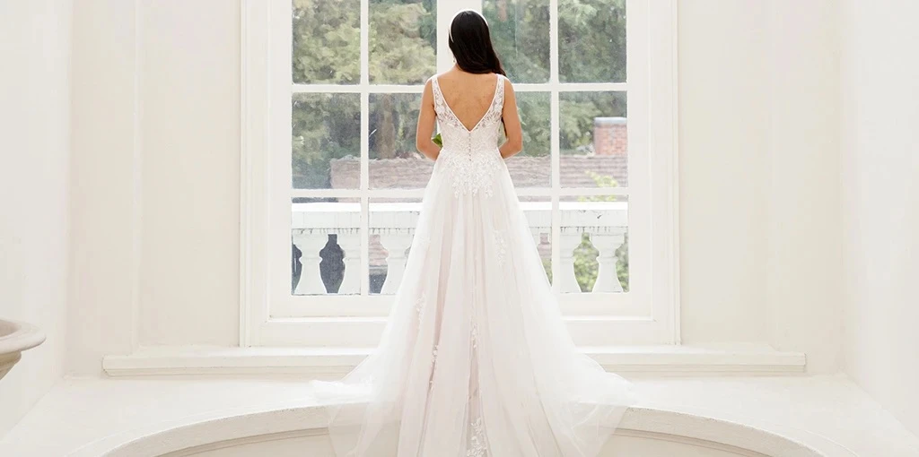 Bride facing a widow wearing a lace a-line wedding dress